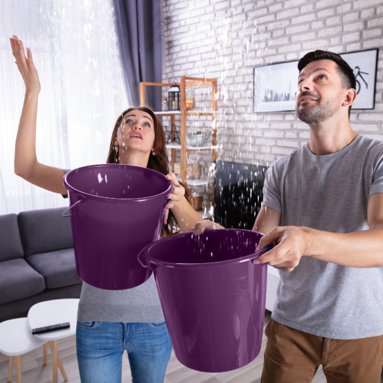 Image of two people holding buckets catching water leaking from the ceiling