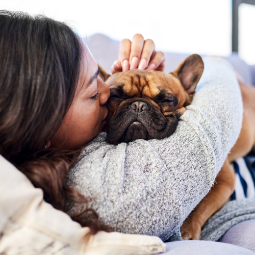 Image of a woman laying with a dog on top of her