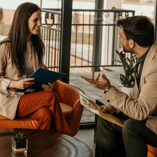 A woman and man smiling discuss paperwork 
