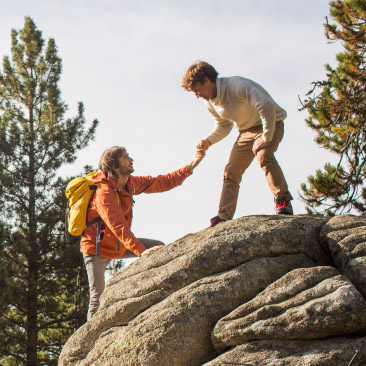 Person helping another up mountain