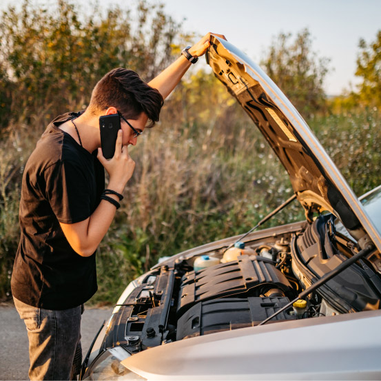 Man standing by broken-down car