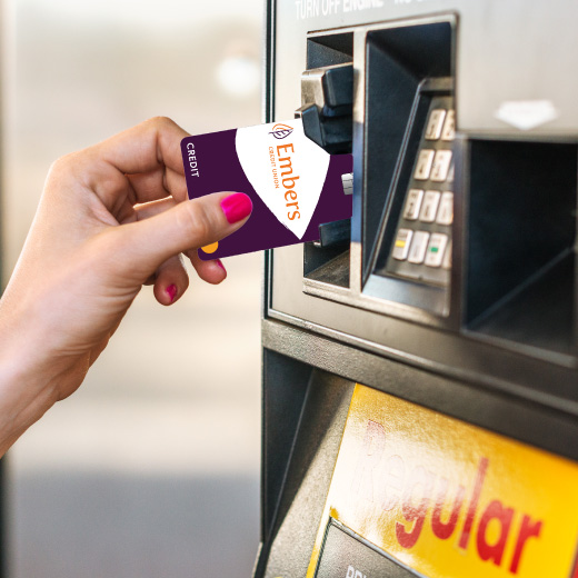 Image of a hand inserting an Embers Credit Card into a gas pump