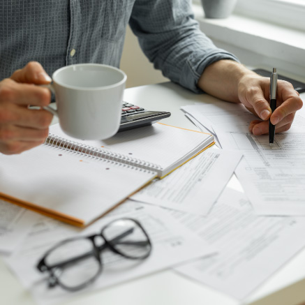 Image of a desk covered in papers with someone writing