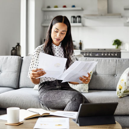 An image of a woman inspecting multiple papers in her hands while in a living room