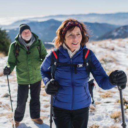 A man and a woman hiking on top of a snowy mountain