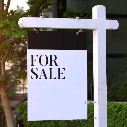 An image of a sign posted in a yard that reads "For Sale"