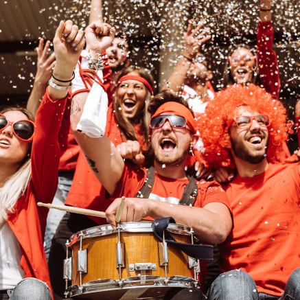 Image of a group of people cheering at an event while confetti falls above them