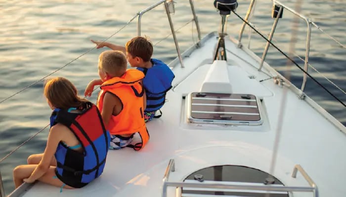 3 kids on a boat with lifejackets