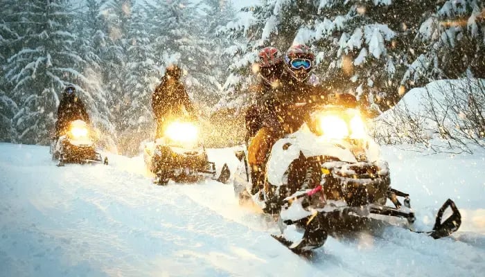 Three snowmobiles on snowy, winter trail