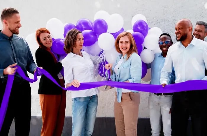 Woman cutting ribbon infront of business