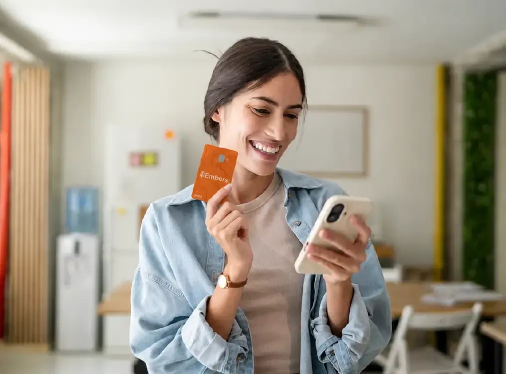 Woman holding Embers Card and looking at phone